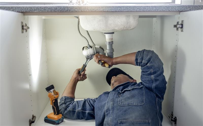 Plumber repairing pipes beneath a bathroom sink in Bradenton