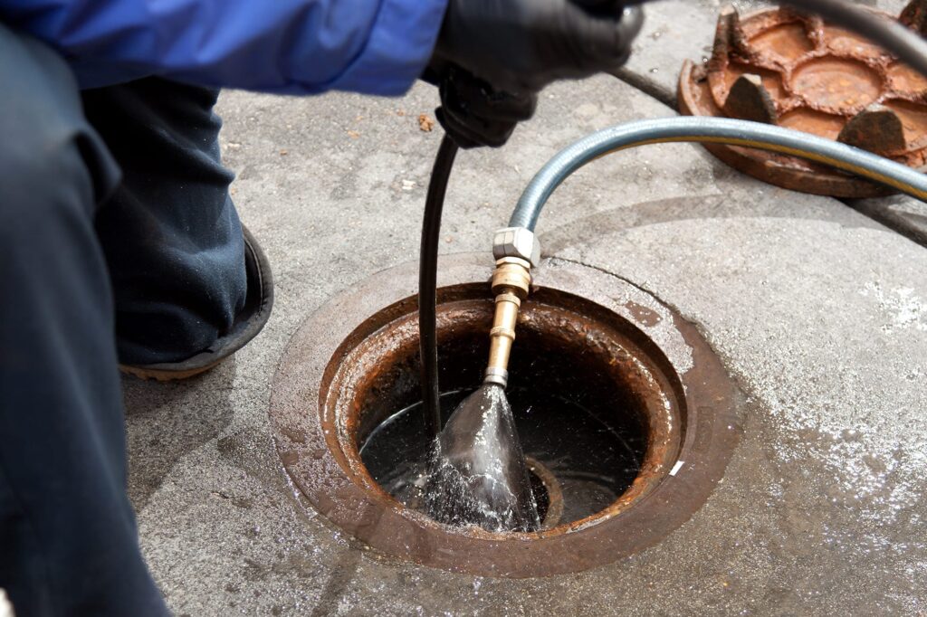 Plumber hydro jetting a sewer line through a manhole in Bradenton