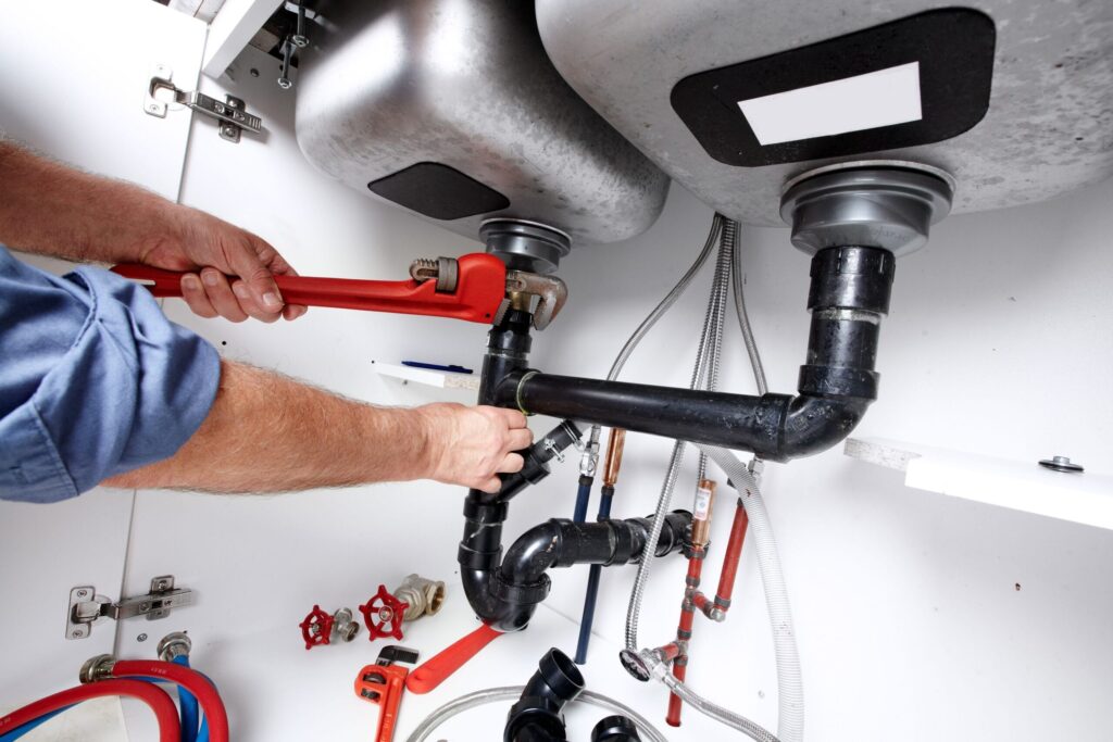Plumber repairing drain pipes beneath a kitchen sink in Bradenton