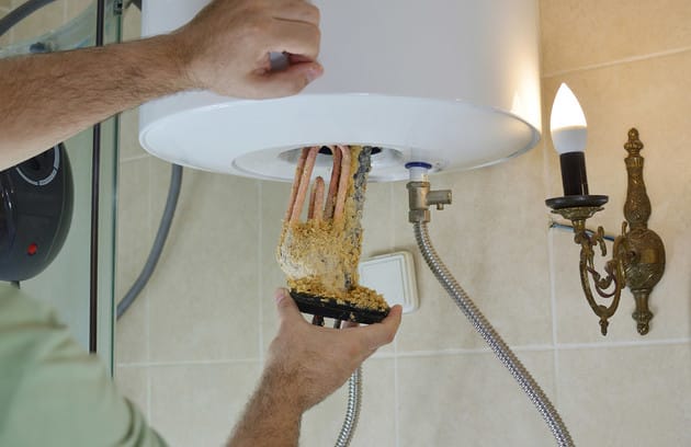 Technician removing mineral buildup from a water heater in Bradenton